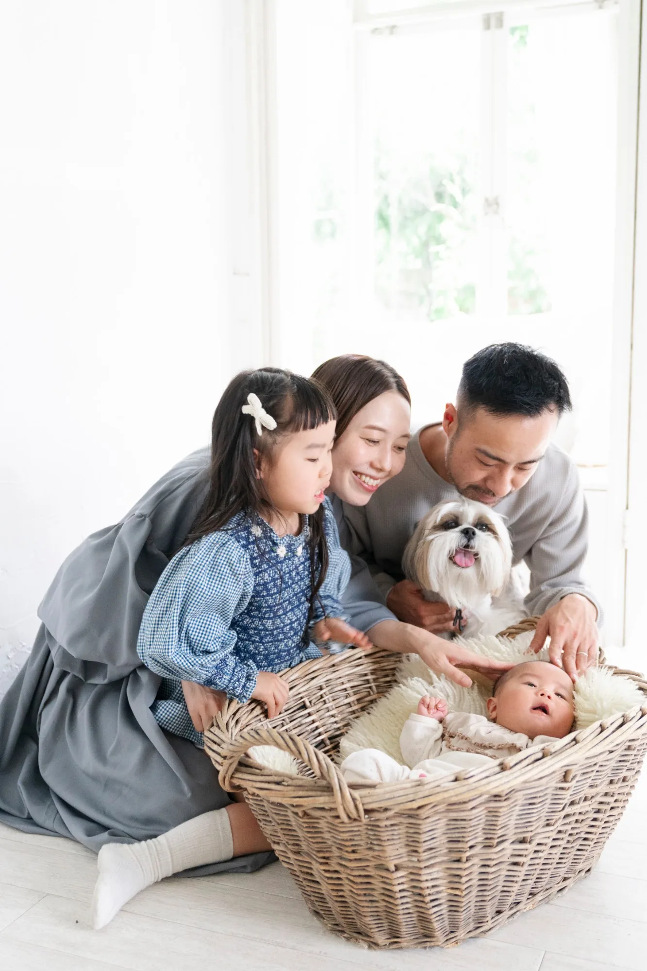 愛犬と赤ちゃんを囲んで笑う家族