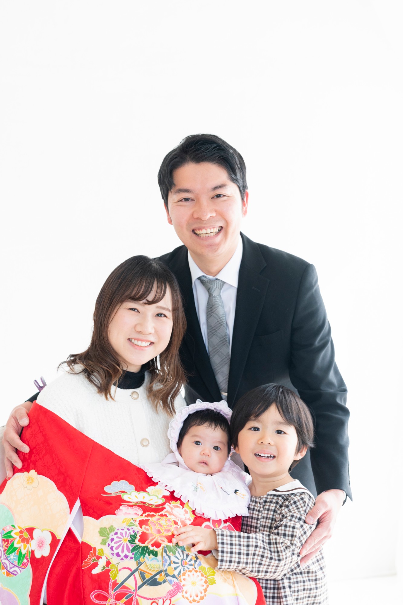 白い背景の前で寄り添う、家族4人の写真